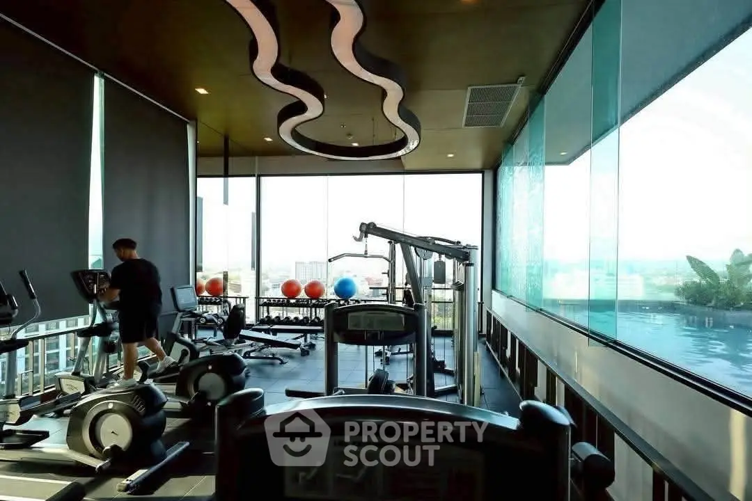 Luxurious gym with modern equipment and stunning poolside view in high-rise building.