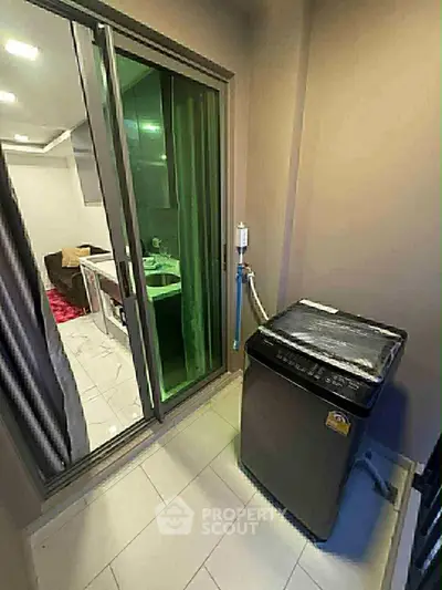 Compact balcony with washing machine and sliding glass door to modern interior.