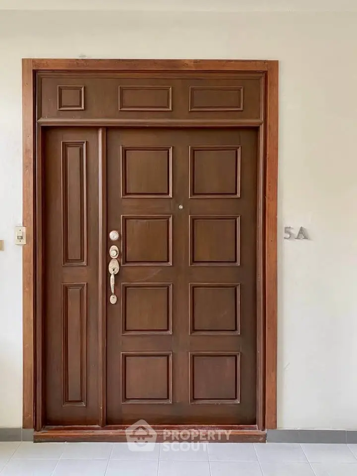 Elegant wooden apartment entrance door with modern security features in a stylish residential building.