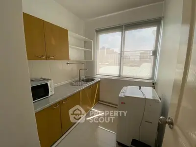 Compact kitchen with natural light, featuring wooden cabinets and modern appliances.