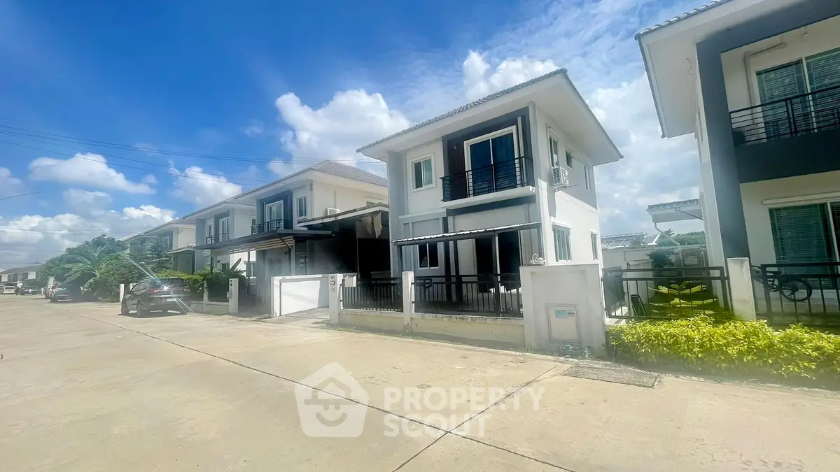 Modern two-story house with sleek design in a suburban neighborhood, featuring a driveway and lush greenery.