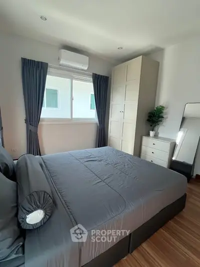 Modern bedroom with sleek design, featuring a large bed, wardrobe, and natural light from a window.
