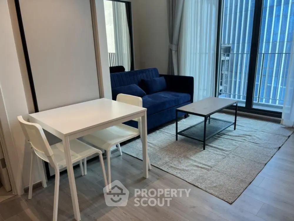 Modern living room with sleek furniture and large windows in urban apartment.
