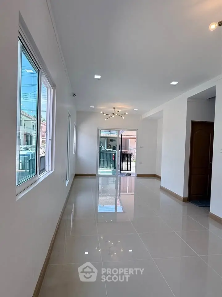 Spacious modern living room with glossy tiled floors and large windows for natural light.