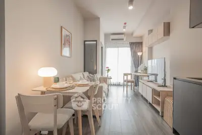 Modern living room with dining area, stylish decor, and natural light from large window.