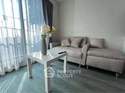 Modern living room with cozy sofa and stylish decor, featuring a bright window view.