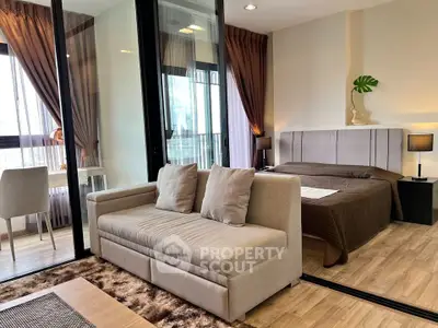 Modern studio apartment with stylish decor and large windows offering natural light.