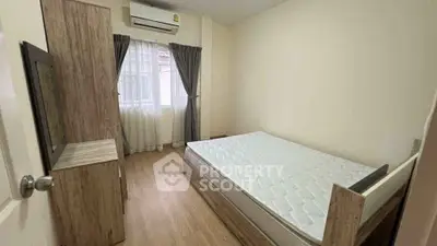 Cozy bedroom with wooden furniture and natural light, perfect for relaxation.