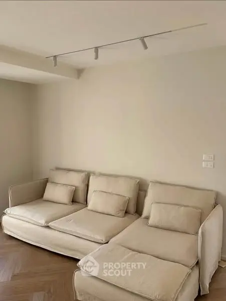 Minimalist living room with beige sofa and modern track lighting