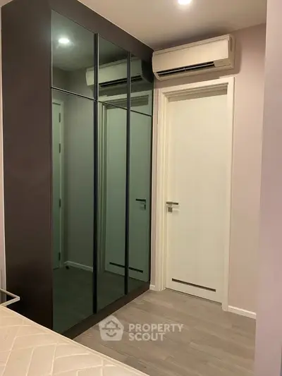 Modern bedroom with sleek mirrored wardrobe and air conditioning unit