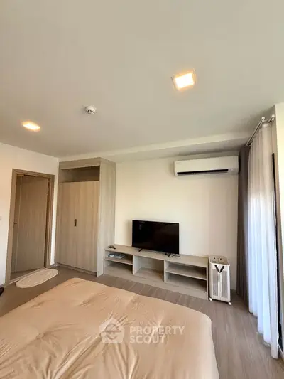 Modern bedroom with sleek design, featuring a wall-mounted TV, air conditioning, and stylish wooden furniture.