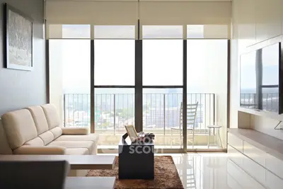 Modern living room with balcony view and sleek furniture in high-rise apartment.
