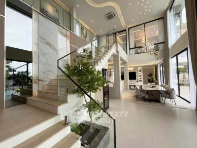 Luxurious modern living room with high ceilings, elegant staircase, and open dining area in a stylish home.