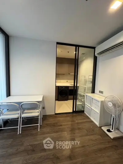 Modern apartment interior with dining area and view into kitchen featuring washing machine.