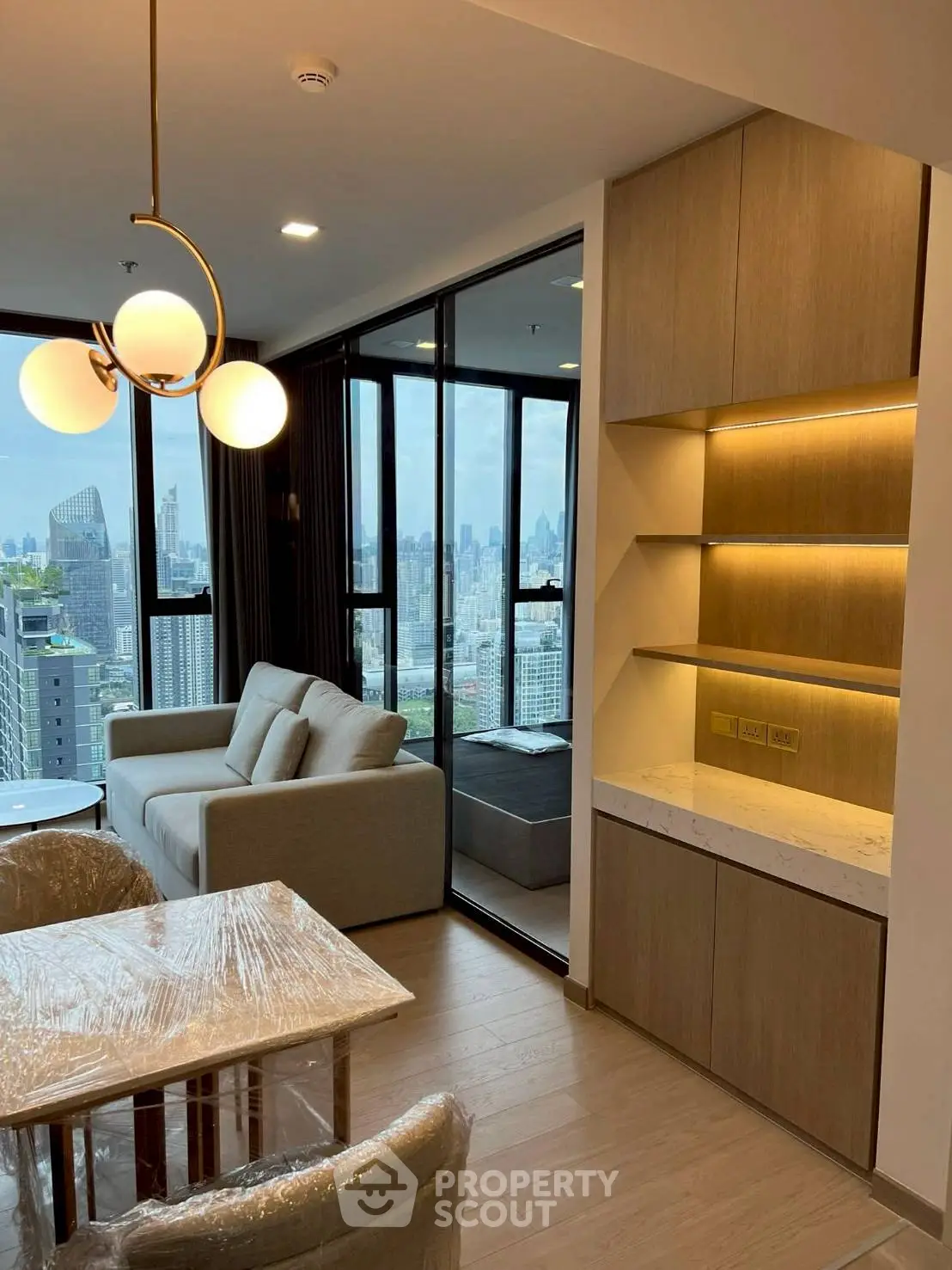 Modern living room with city view, featuring elegant lighting and cozy seating area.