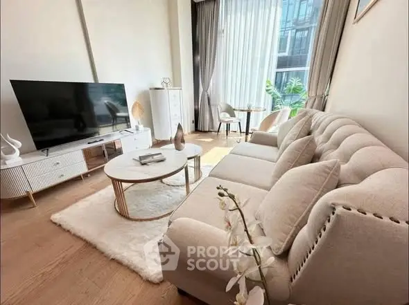 Elegant living room with modern decor, large TV, and natural light from floor-to-ceiling windows.