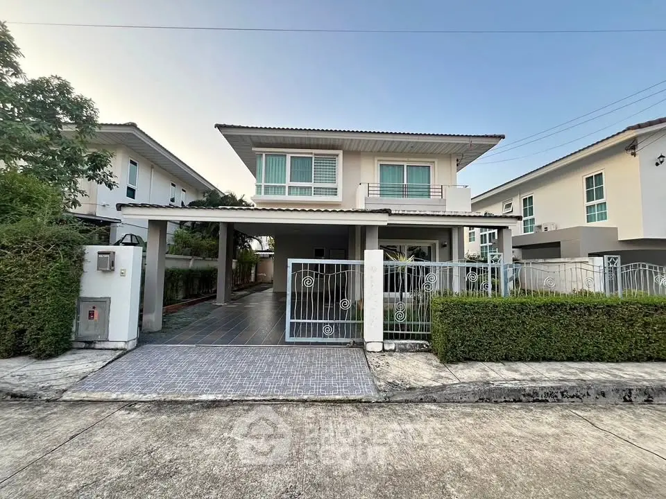 Modern two-story house with gated entrance and driveway in a suburban neighborhood.
