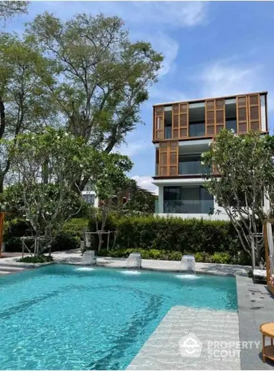 Luxurious modern home with stunning pool and lush greenery, perfect for serene living.