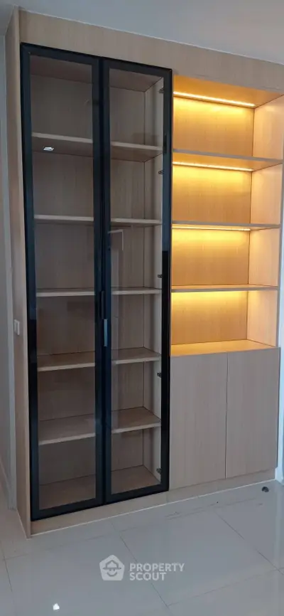 Modern built-in wooden storage unit with glass doors and ambient lighting, perfect for stylish home organization.