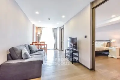 Modern living room with cozy sofa, TV, and dining area leading to a stylish bedroom.