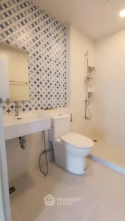 Modern bathroom with stylish geometric tile accent wall and sleek fixtures.