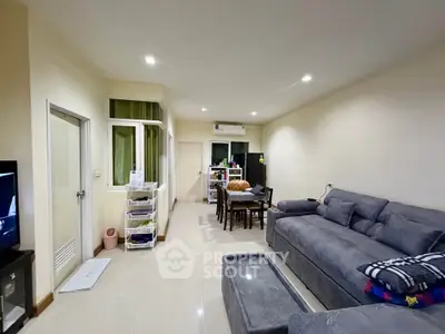 Spacious living room with modern gray sofa and dining area in open layout apartment.