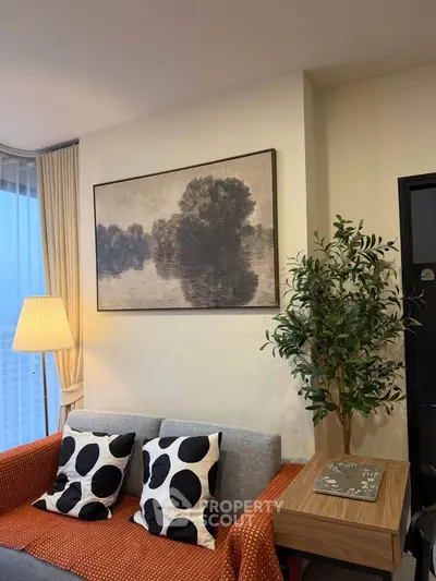 Stylish living room with modern decor, featuring a cozy sofa, elegant lamp, and artistic wall painting.