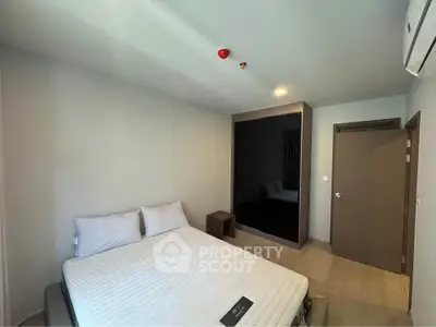 Spacious bedroom with modern design and ample natural light, featuring a comfortable bed and minimalist decor.