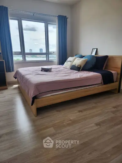 Modern bedroom with large window and wooden flooring, offering a cozy and inviting atmosphere.