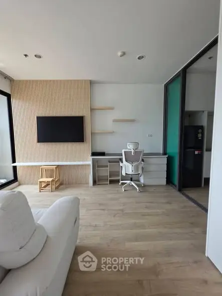 Modern living room with sleek design, featuring a wall-mounted TV, stylish chair, and wooden flooring.