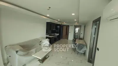 Modern living room with sleek kitchen, marble flooring, and contemporary furniture under renovation.