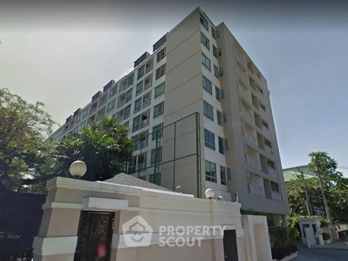 Modern multi-story residential building with lush greenery and secure entrance.