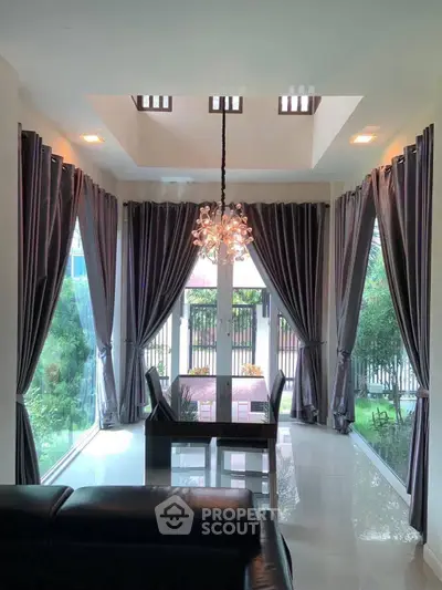 Elegant living room with chandelier and large windows offering garden view