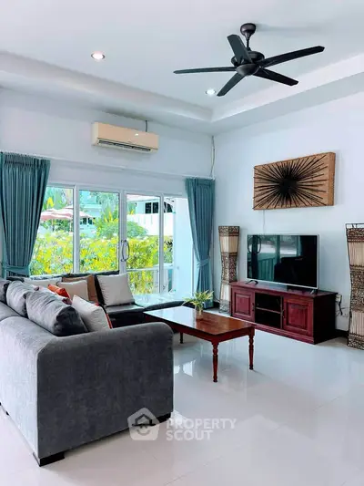 Spacious living room with modern decor and large windows offering lush garden views.