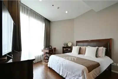 Elegant bedroom with wooden flooring and large window, featuring a cozy bed and stylish decor.