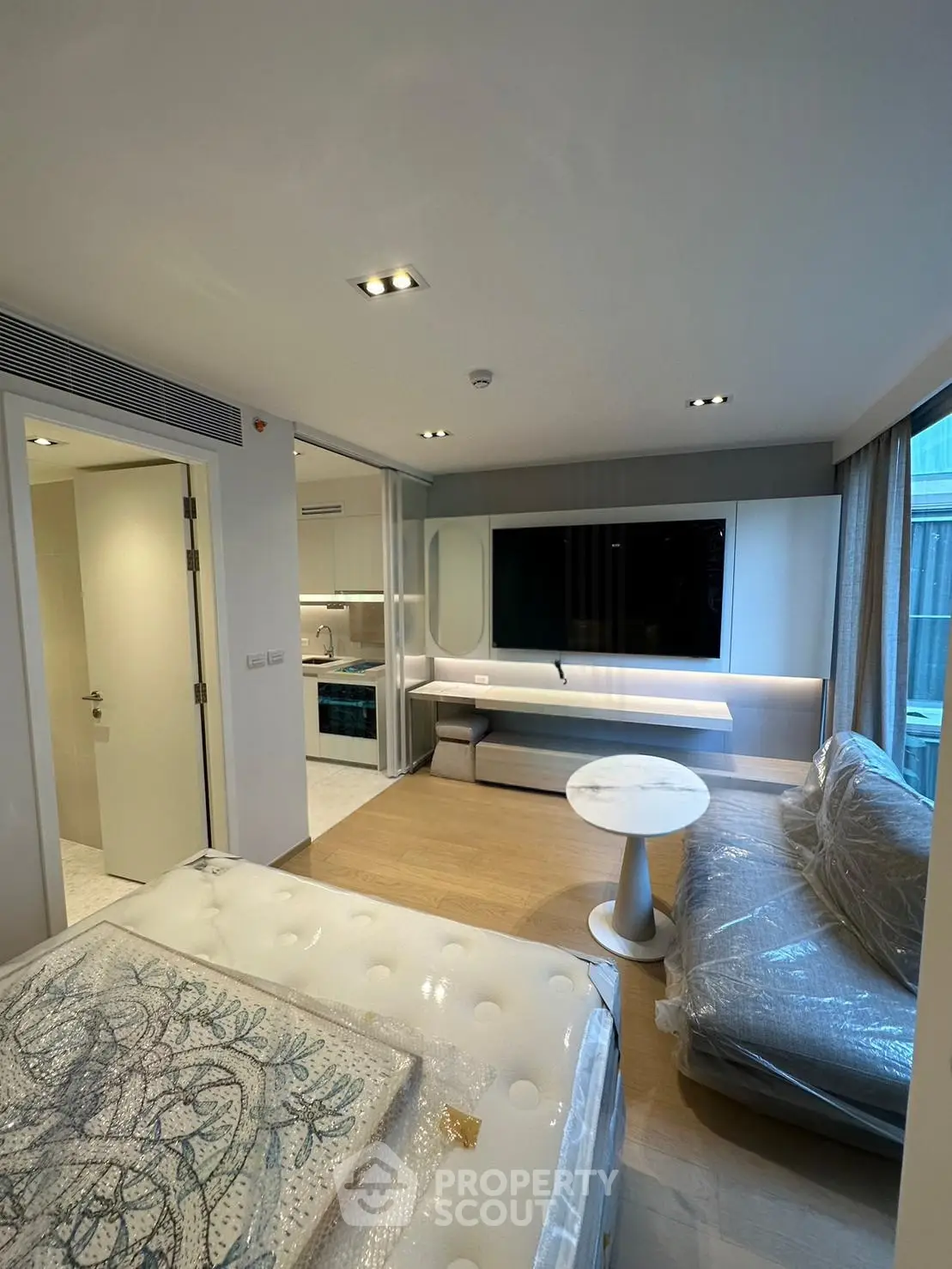 Modern studio apartment with stylish living area and large TV, featuring a cozy bed and elegant decor.