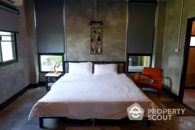 Spacious bedroom with a large bed, industrial chic concrete walls, and modern art, offering a blend of comfort and style.