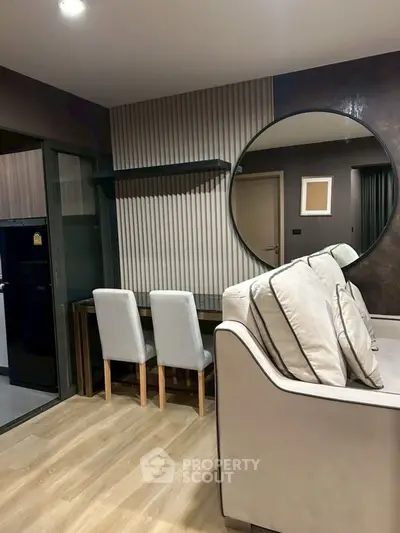 Modern living room with stylish decor and large round mirror