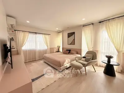 Elegant bedroom with soft lighting, modern decor, and large windows with sheer curtains.