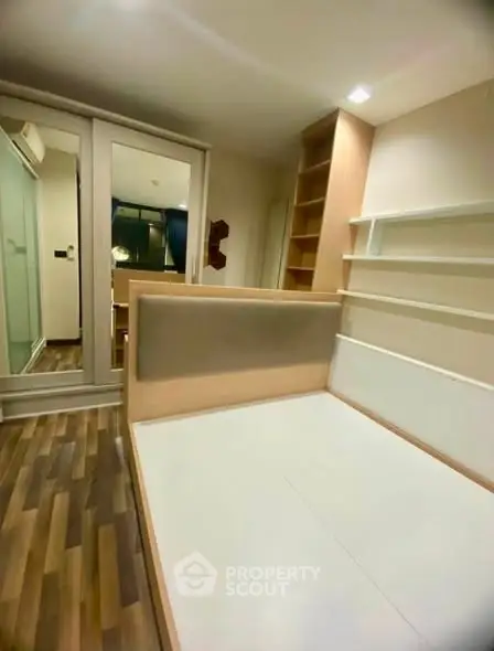 Modern bedroom with stylish wooden flooring and built-in storage solutions.