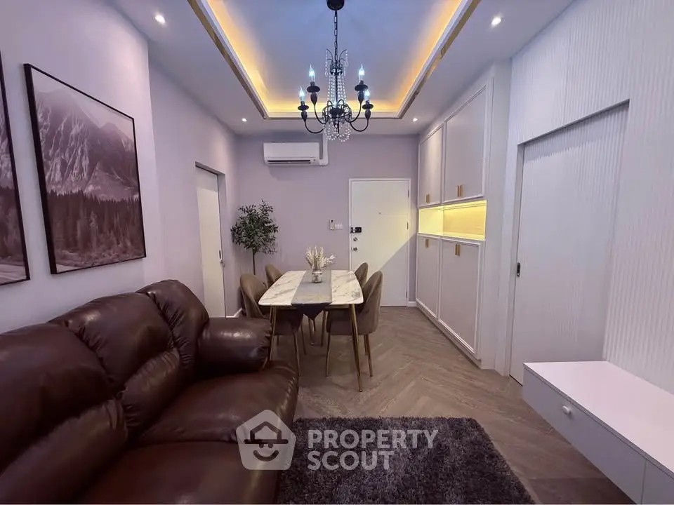 Modern living room with elegant chandelier, leather sofa, and dining area in a stylish apartment.