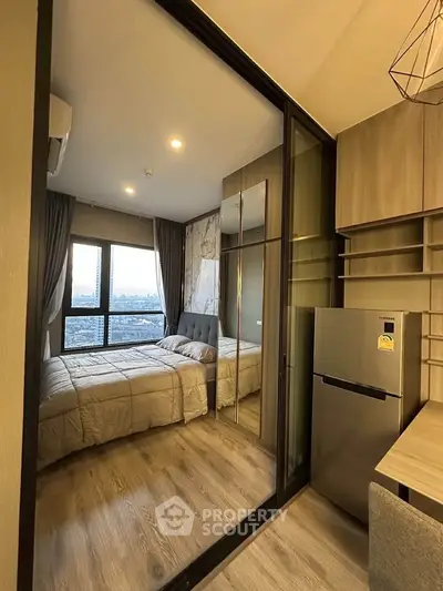 Modern bedroom with glass partition and city view, featuring sleek furniture and wooden flooring.