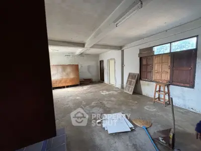 Spacious unfinished room with potential for renovation, featuring large windows and ample natural light.