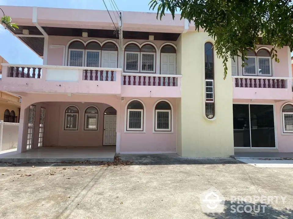 Charming two-story residential building with unique arched windows and spacious driveway.