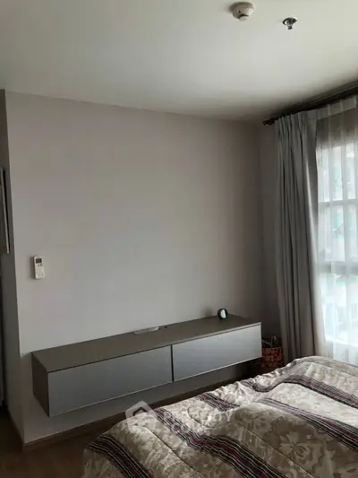 Cozy bedroom with modern decor and natural light from large window.