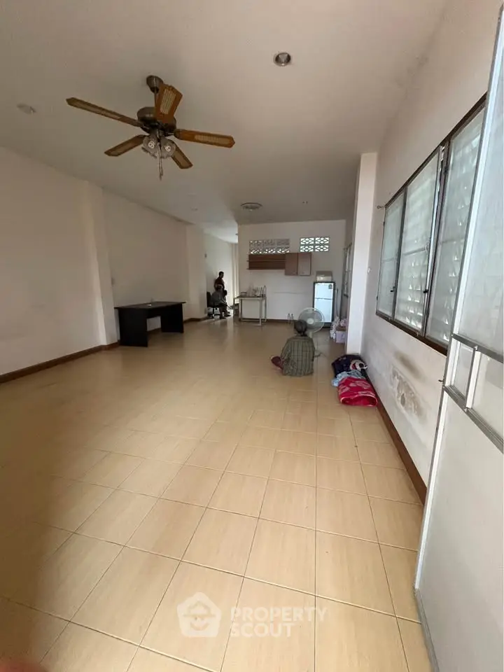 Spacious empty room with ceiling fan and tiled floor, ideal for customization.