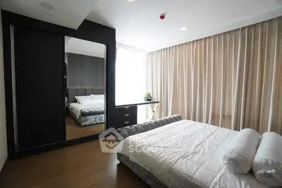 Luxurious bedroom with modern decor and large mirror reflecting natural light.