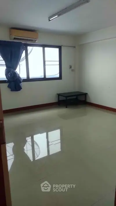 Spacious unfurnished room with large window and air conditioning, perfect for customization.
