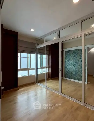 Spacious room with mirrored closet and large windows, perfect for natural light lovers.
