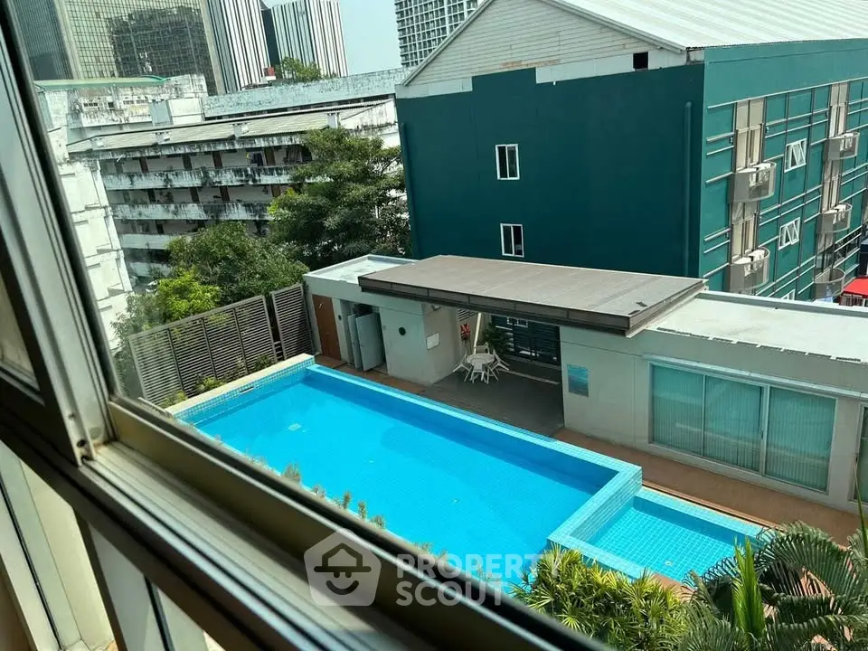 Stunning view of modern apartment complex with pool and lush greenery, perfect for urban living.